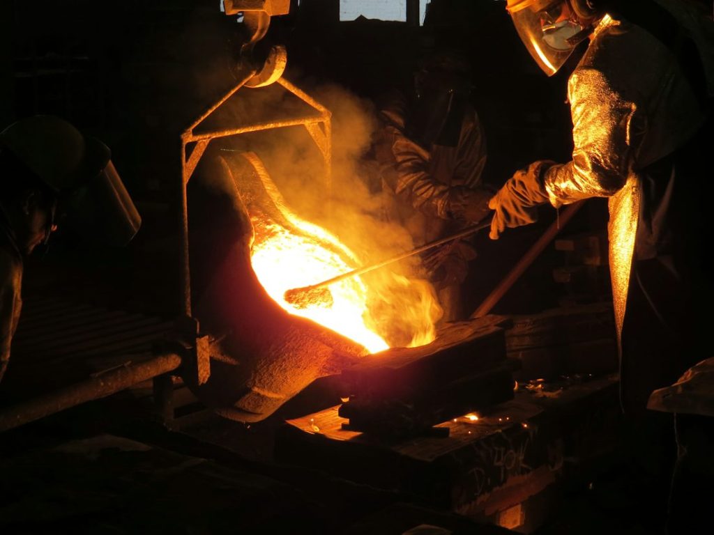 Smith holding glowing iron with tongs