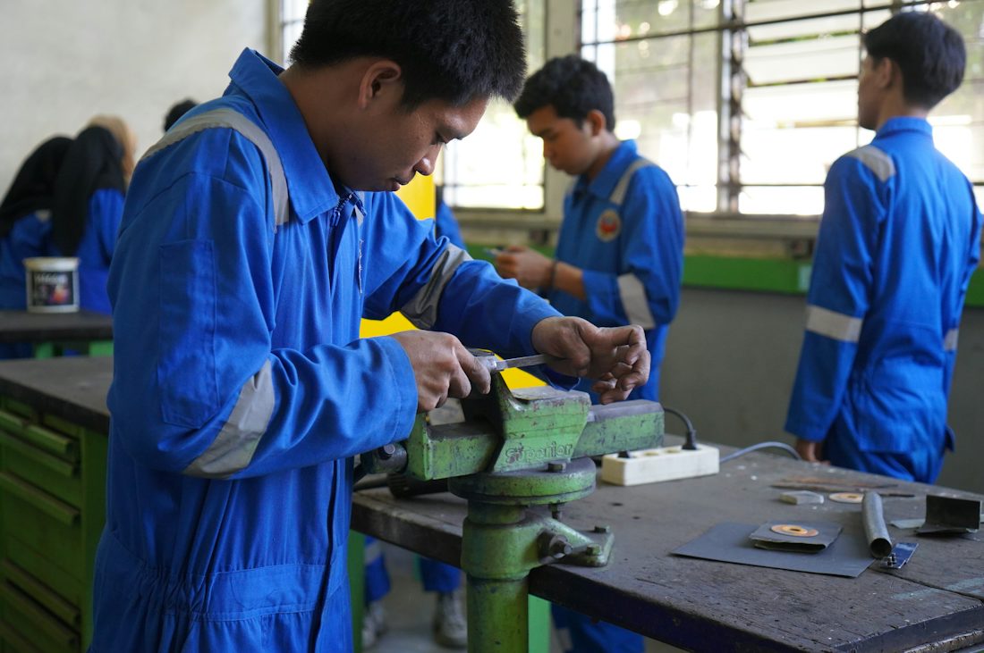 Apprentices working at benches in a training workshop